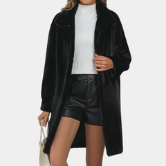 Kvinne i svart fuskepelsjakke, hvit genser og sorte skinnshorts. Moteriktig antrekk for høst og vinter. Trendy dameklær.